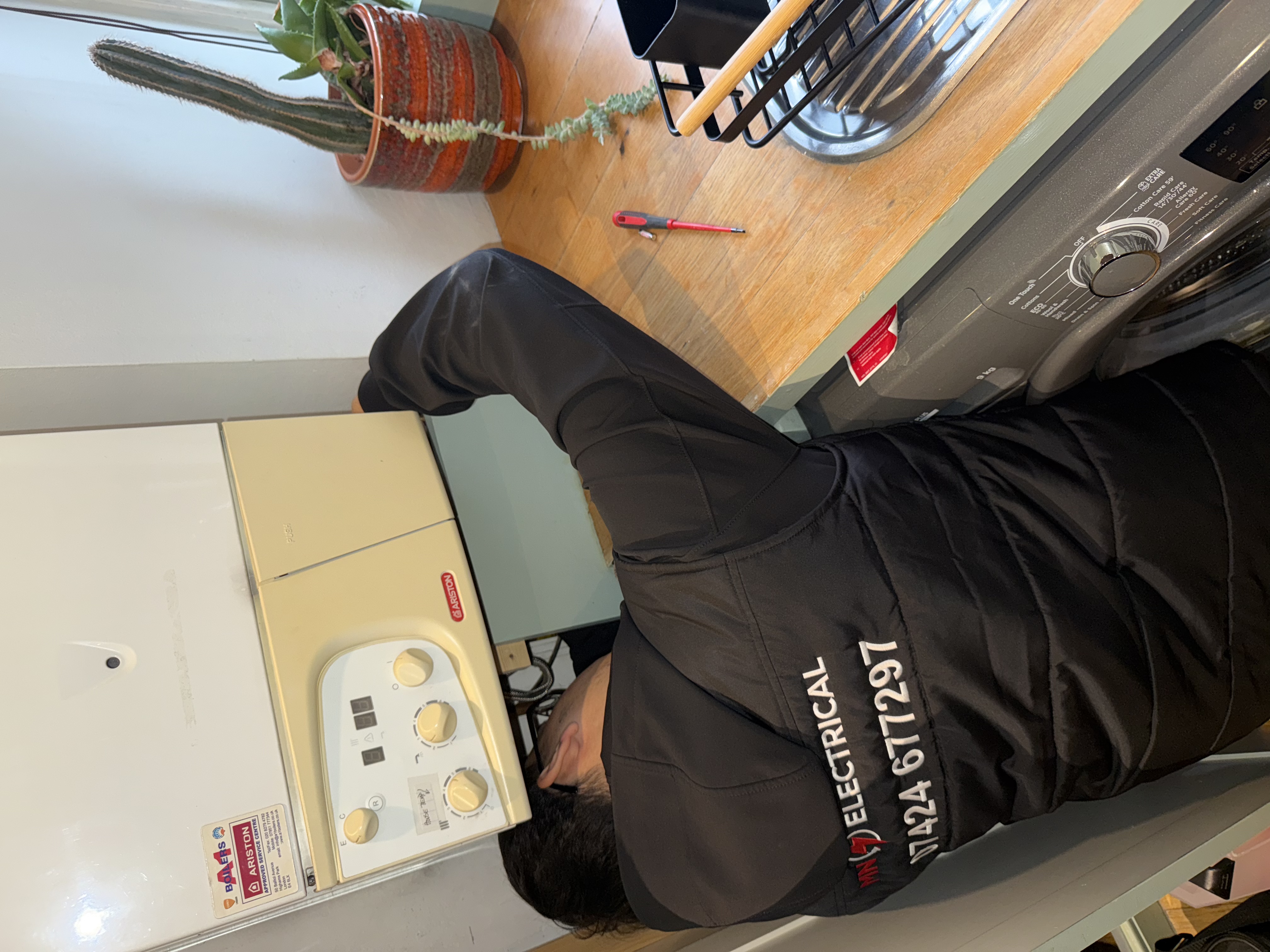 MN Electrical engineer Sulieman inspecting electrical supply and surge damage at boiler connection point — emergency electrical repair London